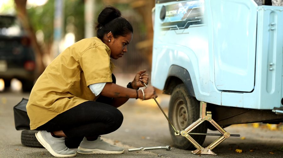 A woman driver jacking up her auto to change a tyre during training